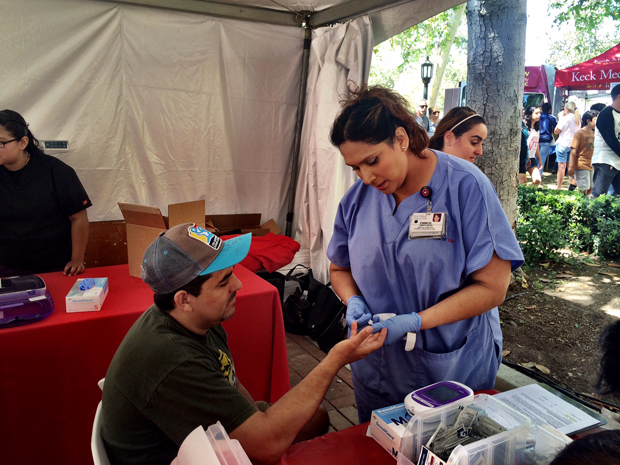 Emmoe Marin, a Keck Hospital of USC medical assistant, checks blood glucose levels of Los Angeles local Alejandro Minera.