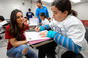 Graduate student Niloo Kossari helps Arianna Rivas as she works on a story. (Photo/Gus Ruelas)