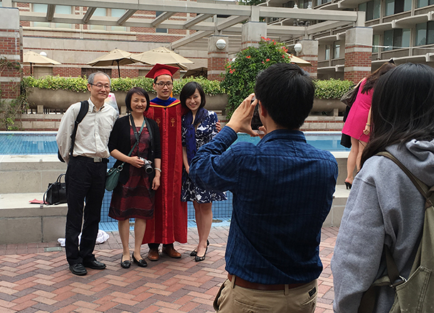 Pingye Zhang, a doctor of philosophy graduate, takes a photo with family members outside of Leavey Library on the University Park Campus, after the commencement ceremony on May 14, 2016.
