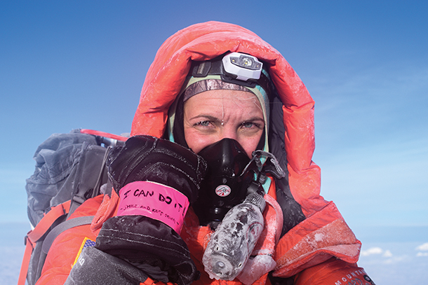 Vanessa Blasic poses at the summit of Mount Everest, showing off her pink duct tape band that says, “I can do it!”