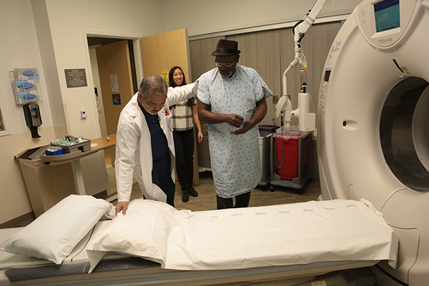 Kirkland Haynes, right, is led to a CT machine, as he prepares to receive a low-dose CT screening during a recent appointment.