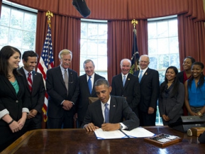 USC physical therapy student Zuleima Hidalgo (third from right) looks on as U.S. President Barack Obama signs a student loan bill to keep students’ interest rates low during a signing ceremony in the Oval Office of the White House in Washington, D.C., on August 9. (Photo/Saul Loeb/AFP/Getty Images)