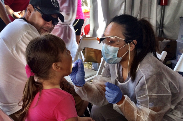 Irene Esteves, dental hygienist at the Ostrow School of Dentistry of USC Faculty Practice, examines the teeth of a festival participant.