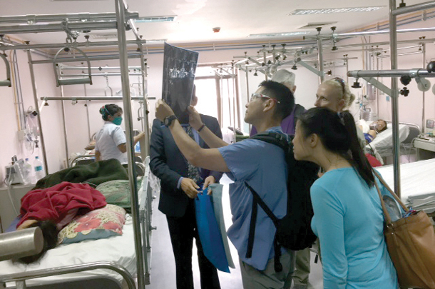 Team leader Kenji Inaba and his colleagues look at images from post-operative patients during rounds in a trauma center in Kathmandu. 
