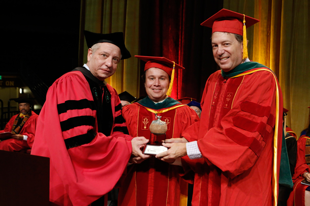 Dean Carmen A. Puliafito, MD, MBA, left, joins Etan Chaim Milgrom, MD, MS, right, to present the inaugural award for compassionate care to Joshua Sapkin, MD, at the Keck School of Medicine commencement.