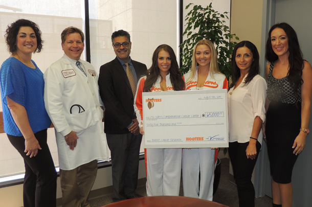 Jaime Valvano, at left, of the V Foundation for Cancer Research and three representatives from Hooters of Orange County present a check to USC Norris Director Stephen B. Gruber, second from left. Also pictured, from Gruber's left, are Zul Surani, executive director of the HSC Community Partnerships Office in Civic Engagement,  Jordyne Chessmore and Shelby Tweeten of Hooters, Elena Nieves, Clinical Trials Outreach and Enrollment coordinator, and Melissa Fry, director of marketing for Hooters.