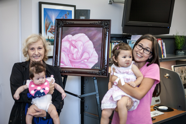 Artist Erna Braun poses with granddaughters Lauren, Sofia and Jasmine in front of a painting from Braun’s Hope Rose Collection.