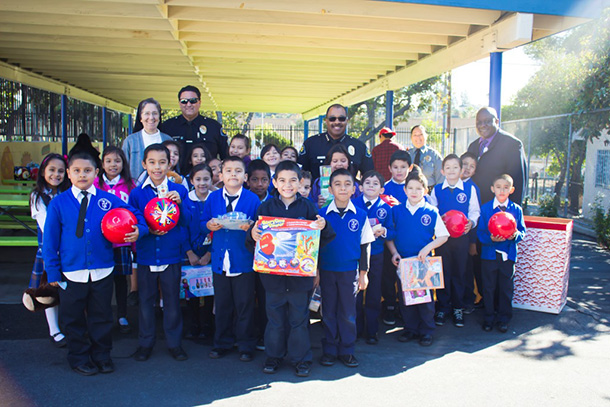 Keck Medicine of USC and USC Department of Public Safety officials visit with students from Santa Teresita School to drop off presents from a holiday toy drive on Wednesday, Dec. 16, 2015. Back, from left, are Sister Mary Catherine, DPS Sgt. Roland Gallardo, Chief John Thomas, Community Service Officer Monica Sandoval and healthcare security director Charles Holloway.