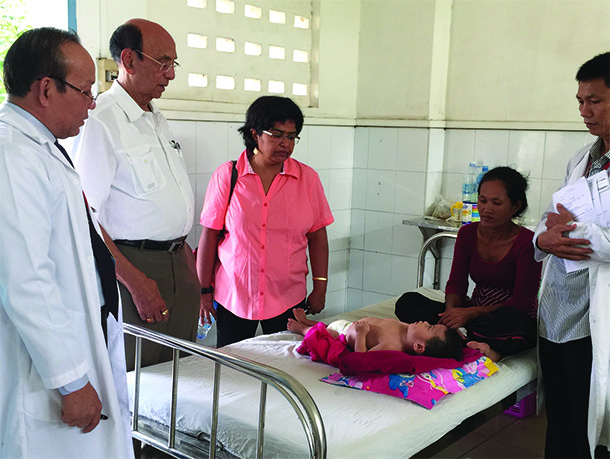 Shri Mishra, second from left, and Soma Sahai-Srivastava, center, look at a child in a clinic in Cambodia during a July 2015 trip to the country. Sahai is spearheading a group of medical professionals from the Keck School who are developing a neurology outreach program for Cambodian health care professionals funded by a grant from the World Federation of Neurology.