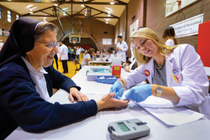 USC School of Pharmacy student Alana Bell gives Sister Mary Catherine Antczak a cholesterol test during the USC Civic Engagement's Health and Fitness Fair, held March 27, 2016, at Hazard Park. (USC Photo/Gus Ruelas)