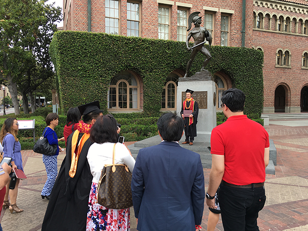 Anthony Wong, a master of global health graduate, has his photo taken in front of Tommy Trojan after commencement on May 14, 2016, at the University Park Campus.