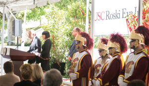 Edward Roski, left, speaks while wife Gayle Roski, USC President C. L. Max Nikias and members of the Trojan Marching Band look on, during a celebration of the naming gift for the USC Gayle and Edward Roski Eye Institute on April 28 at Harry and Celeste Pappas Quad on the Health Sciences Campus.
