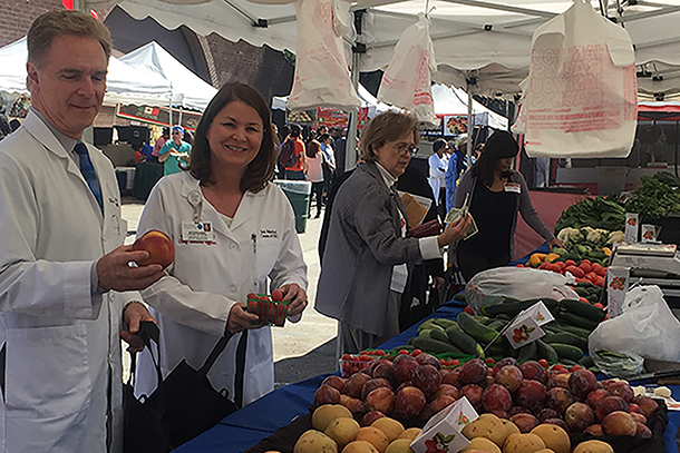 Steven Giannotta, MD, chair of neurological surgery, left, and Stephanie Hall, MD, chief medical officer for Keck Medicine of USC, look at produce for sale at the new Keck Farmers Market, Oct. 4 at Hazard Park.