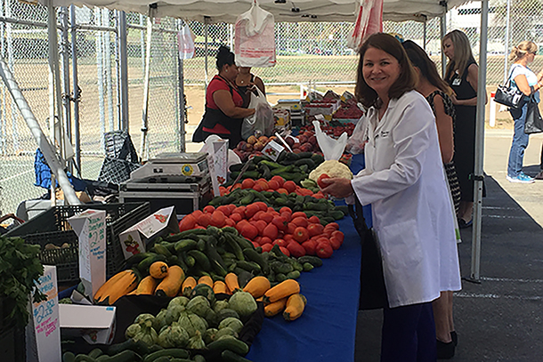 Stephanie Hall, MD, chief medical officer of Keck Medical Center and USC Norris Cancer Hospital, looks at produce at the new Keck Farmers Market, Oct. 4 at Hazard Park. (Photo/Virginia Baca)