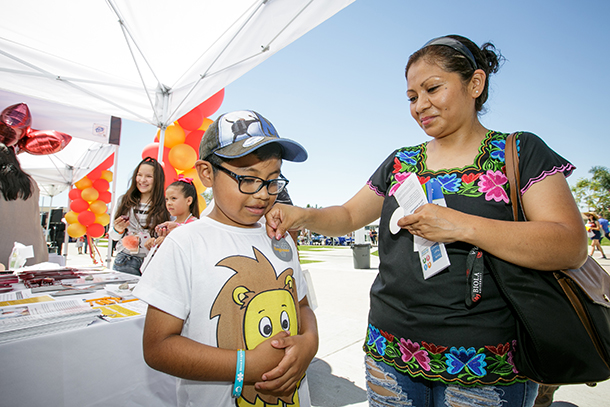 Matthew Lopez, 7, gets a sticker put on at the USC booth by mom Monica Lopez at the Univision Health Fair held June 17 at East Los Angeles College in Monterey Park.