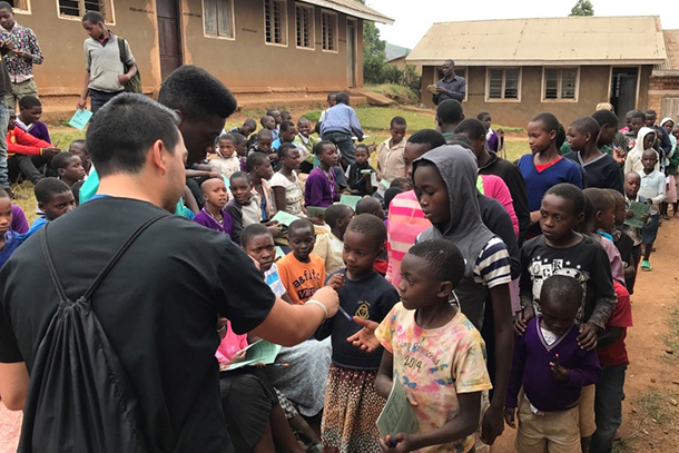Global Medicine students recently shared their experiences conducting international research during the Global Citizenship Roundtable. Here, students participating in the Uganda course give school supplies to local children.
