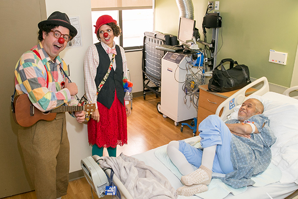 Medical clowns Zachary Steel and Caitlyn Conlin visit patient Antonio Revlando at USC Norris Cancer Hospital.
