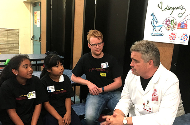 Martin Kast explains an experiment to two elementary school students in the cancer education workshop organized by the Joint Educational Project's Young Scientists Program, while graduate student Ruben Prins looks on.
