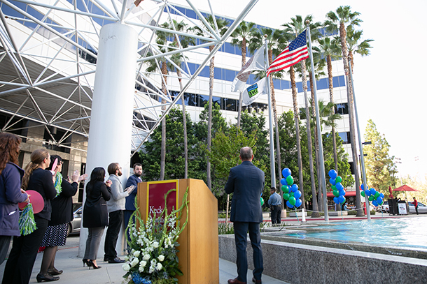 Staff members and administrators watch the Donate Life flag being raised in front of Keck Hospital of USC.
