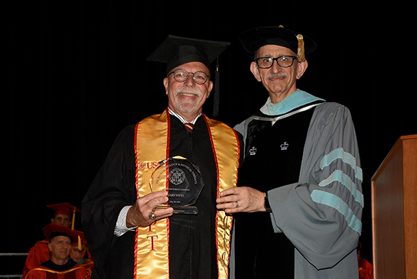 Former Lakers trainer Gary Vitti, left, holds a plaque commemorating his role as commencement speaker at the May 10 ceremony of the USC Division of Biokinesiology and Physical Therapy, and is joined by James Gordon, associate dean and chair of the division.