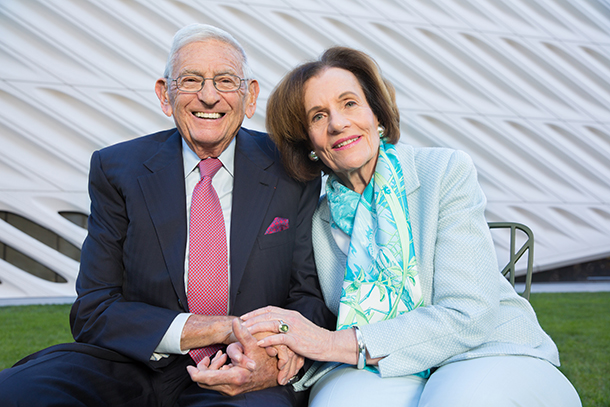 A smiling older couple sits outdoors
