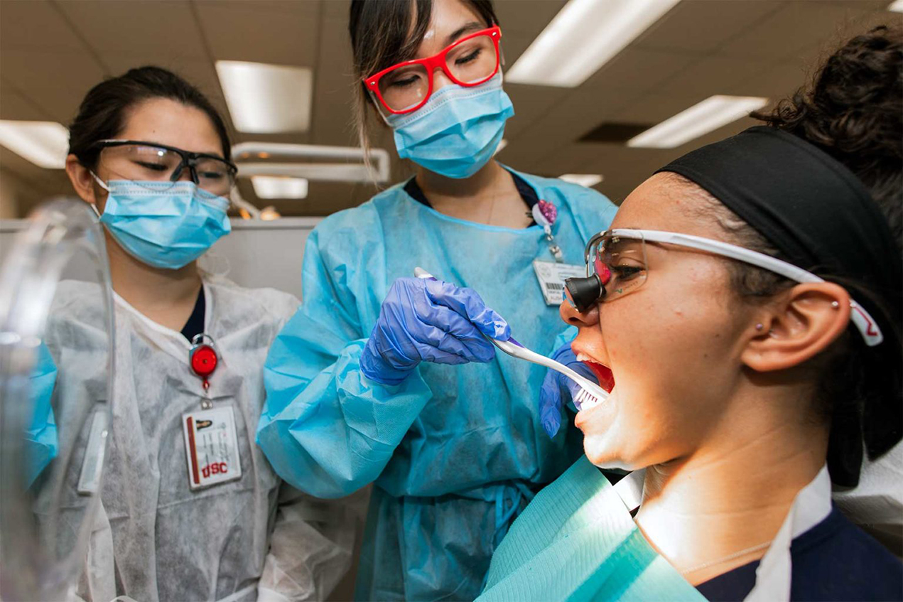 Dental hygiene student Alisha Lee teaches dental students Cindy Tashiro and Taylor Purks different brushing methods. As part of the curriculum change, dental hygiene students work alongside dental students in the clinic.