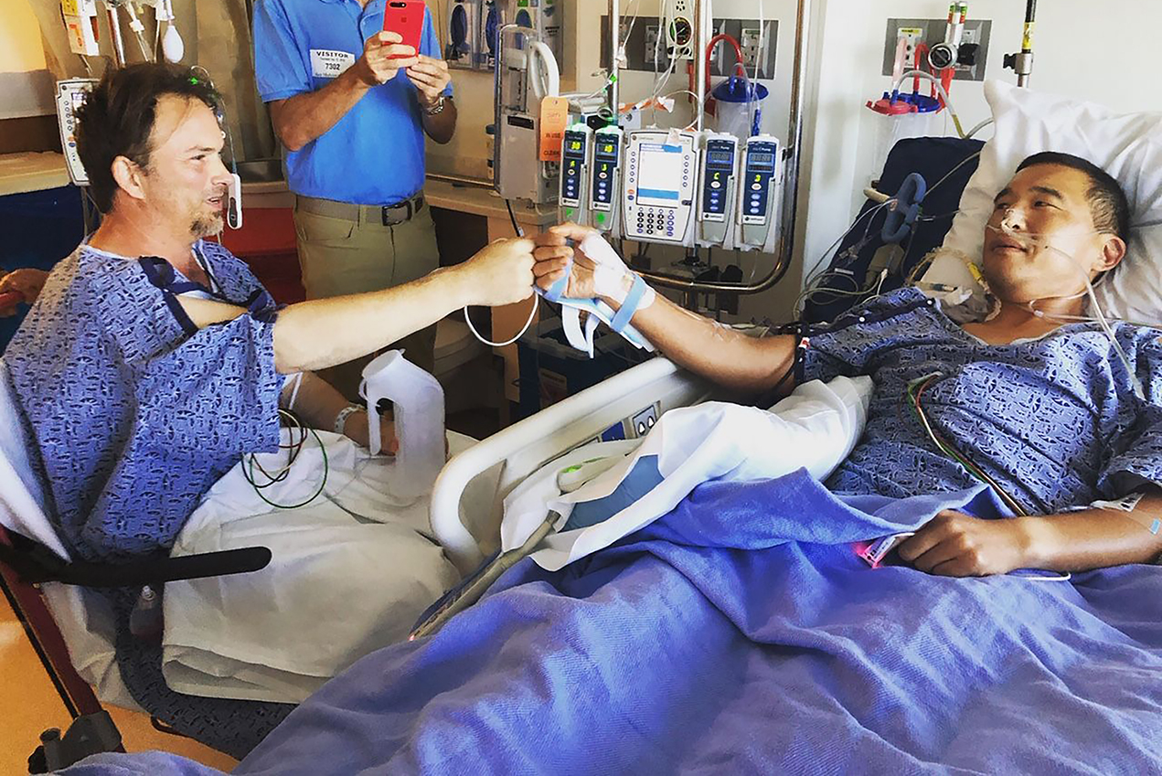 Two hospital patients share a fist bump.