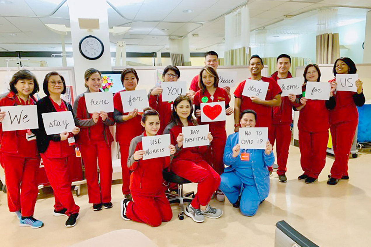 Nurses hold signs reading: We stay here for you. Please stay home for us.