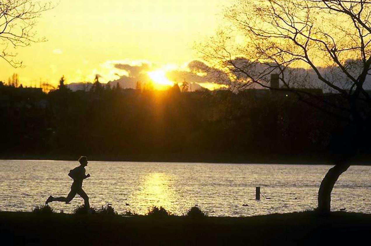 An athlete runs in the light of a low sun.