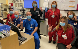 Clinicians in protective masks give the peace sign.