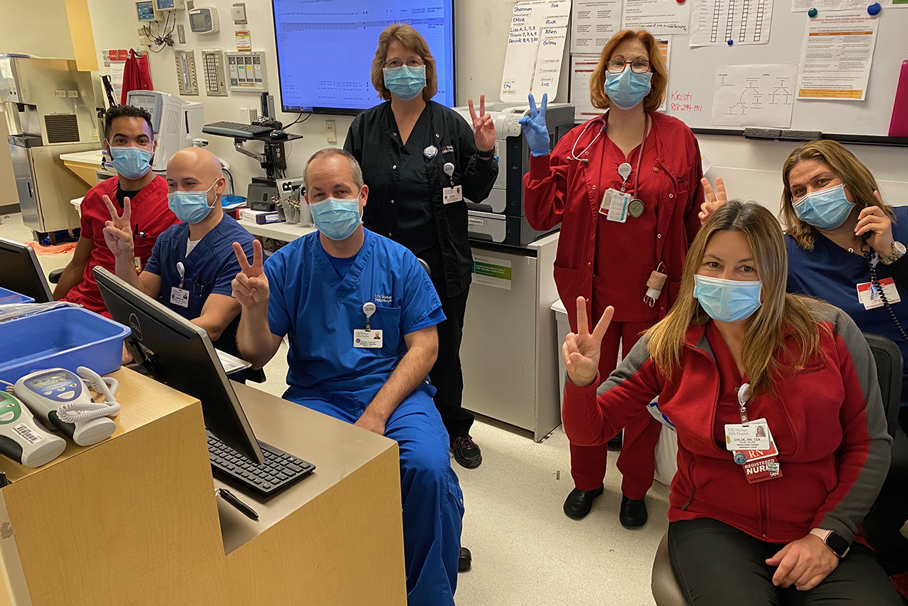 Hospital staff members wearing protective masks give the peace sign.