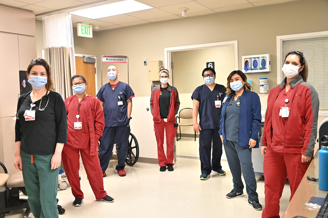 Clinicians in protective masks stand in a V formation.