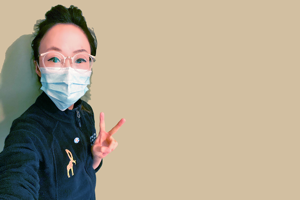 A woman wearing a protective mask gives the peace sign.