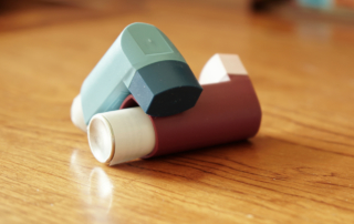 Two inhalers rest on a wooden surface.