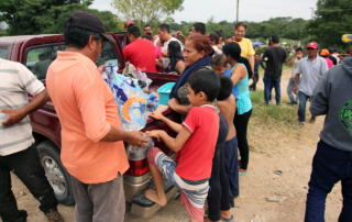 South American families accept donated supplies in a clearing.