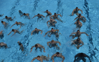 A group of men exercise in an olympic pool.