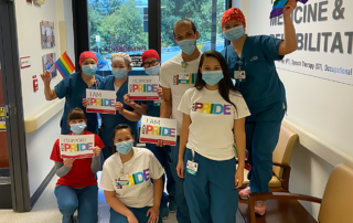 Medical professionals in masks wear T-shirts and bear signs reading Keck PRIDE.