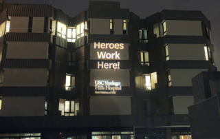 Projected words on a building read, "Heroes work here. USC Verdugo Hills Hospital."