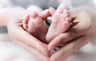 A woman's hands cradle the feet of a newborn.