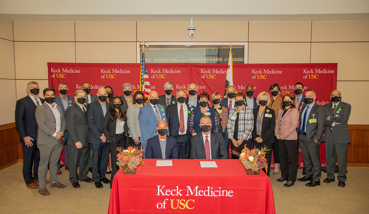 A group of businesspeople stand in front of signs that say Keck Medicine of USC