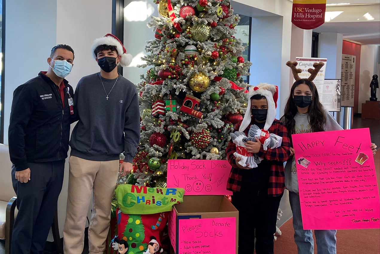 Armand Dorian, MD, MMM, with his children, from left, Avand, Hooys and Jivan. The trio collected more than 250 pairs of socks for unhoused individuals who seek care at USC-VHH's Emergency Department.