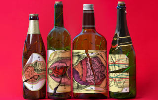 Three empty alcoholic beverage bottles bear tattered labels featuring human body parts.