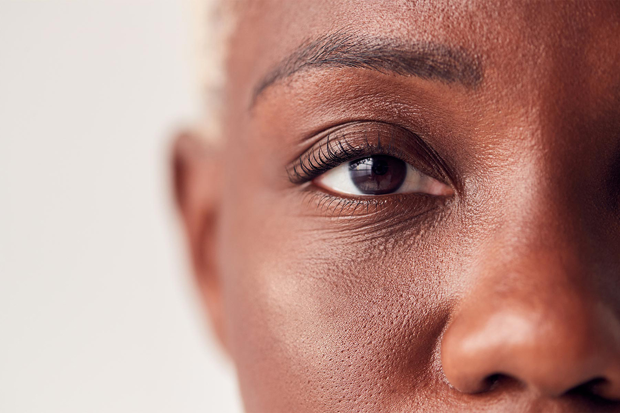 A closeup of a woman's face focuses on her dark brown eye.