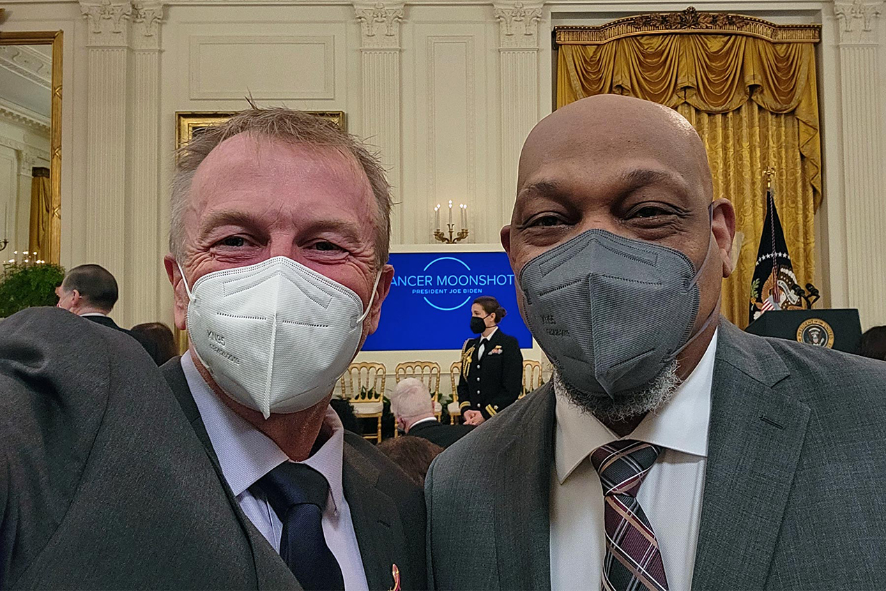 Two men wearing masks take a selfie inside the White House