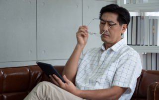 An older man reads a tablet with a concerned expression.