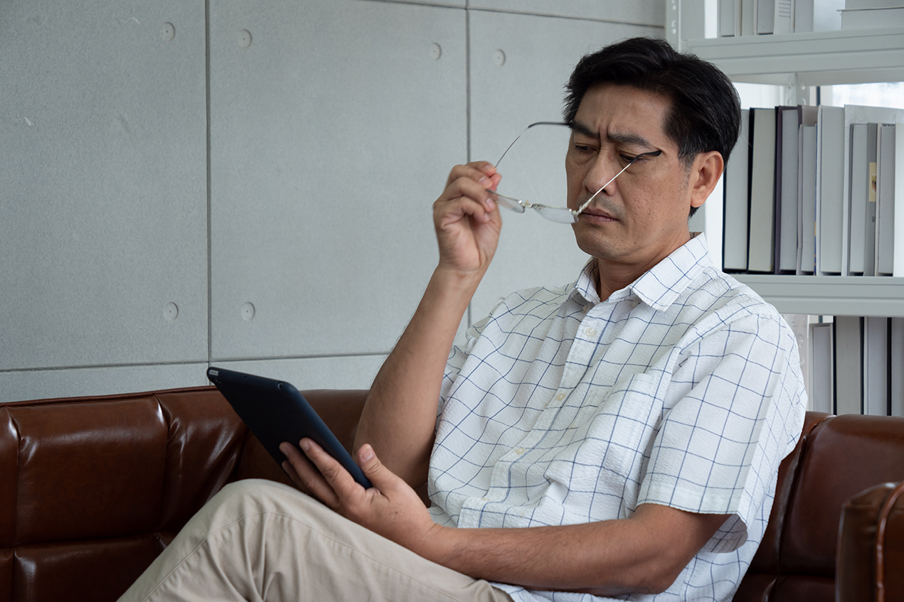 A middle-aged man frowns as he reads a tablet