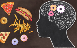 A chalkboard illustration depicts a brain with turning gears inside a head that faces an array of unhealthy foods.