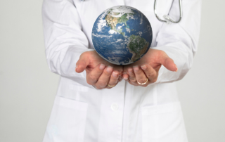 A doctor's hands hold out a small, realistic model of the planet Earth.