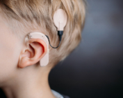 A closeup shows a small child wearing a cochlear implant