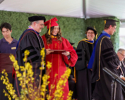 At a graduation ceremony, a dean presents a student with a diploma